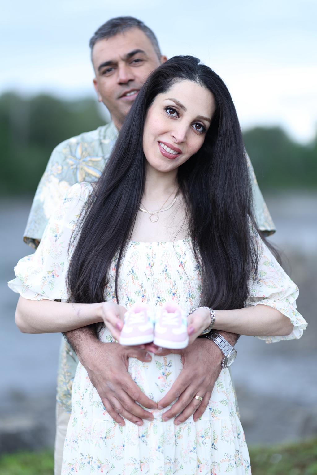 Close maternity portrait of expecting parents holding pink baby shoes
